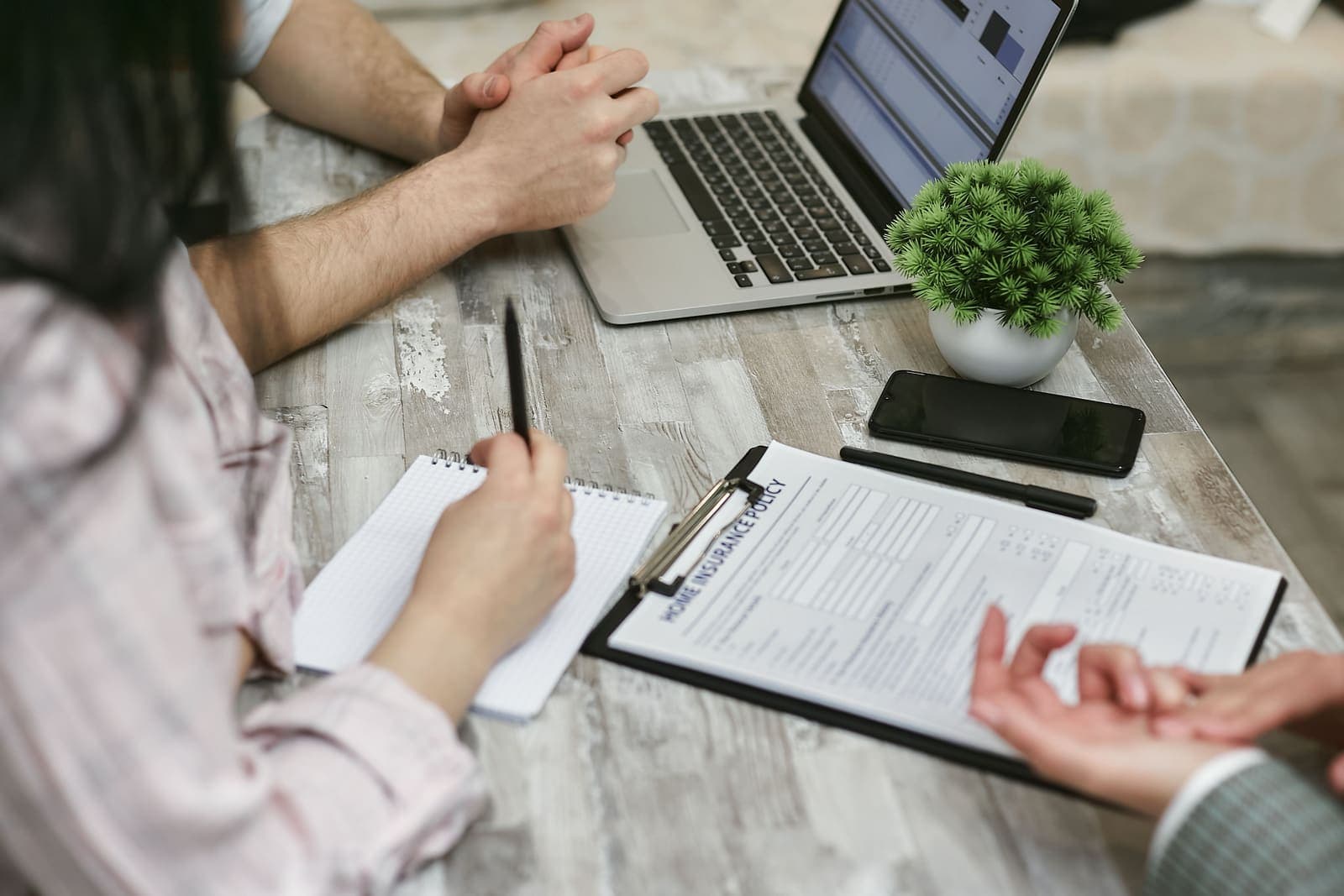 Échange autour d'un contrat d'assurance, avec ordinateur portable et notes