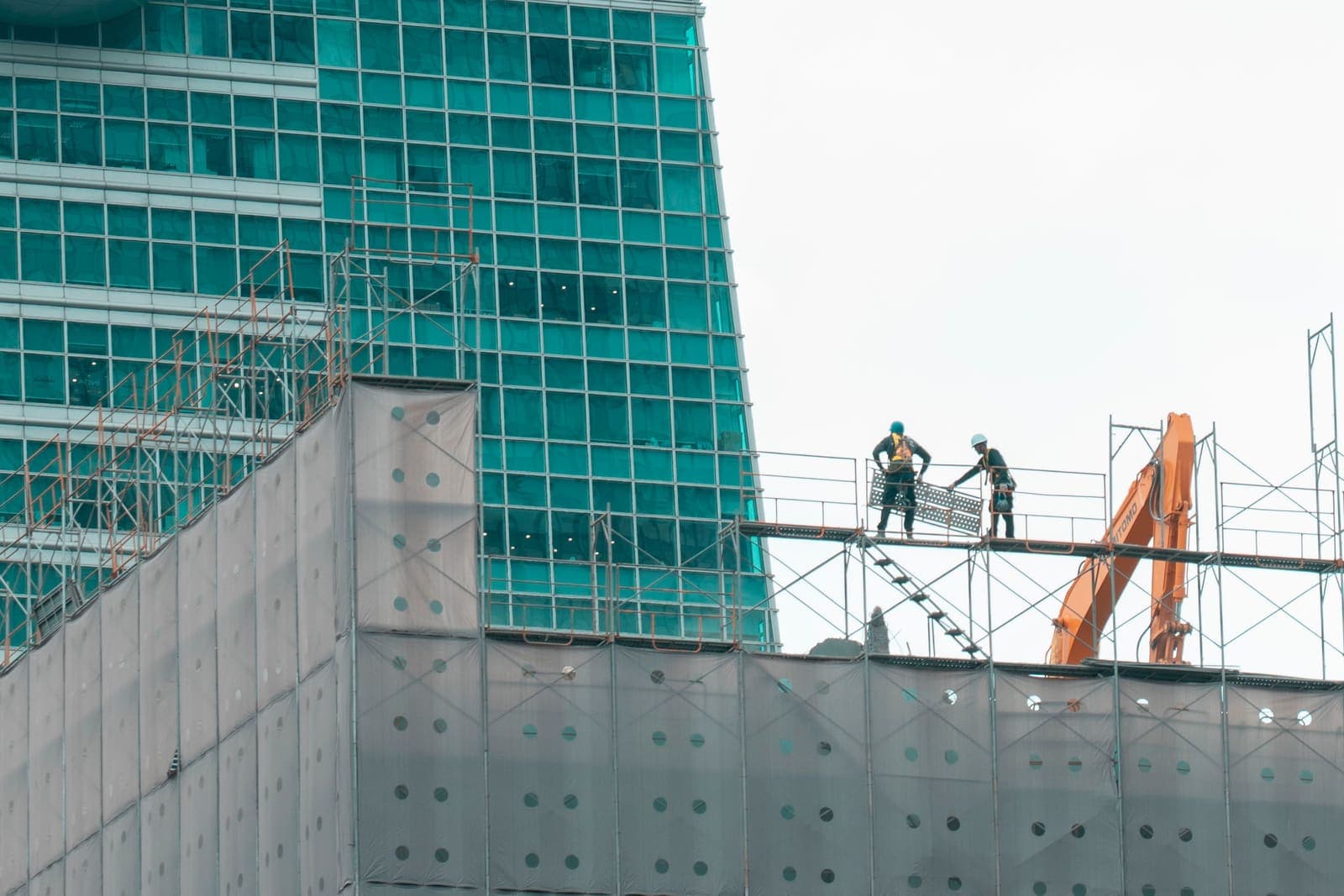 Deux ouvriers sur un échafaudage devant un immeuble en construction